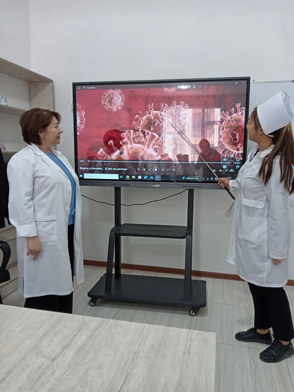 A teacher and a student reviewing a microbiology topic on an interactive screen